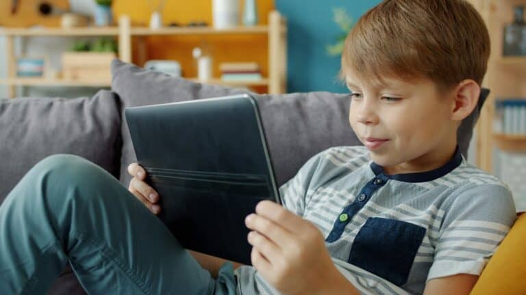 Child sitting on a sofa watching a video on a tablet